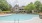 Swimming pool in front of building surrounded by trees and orange chairs